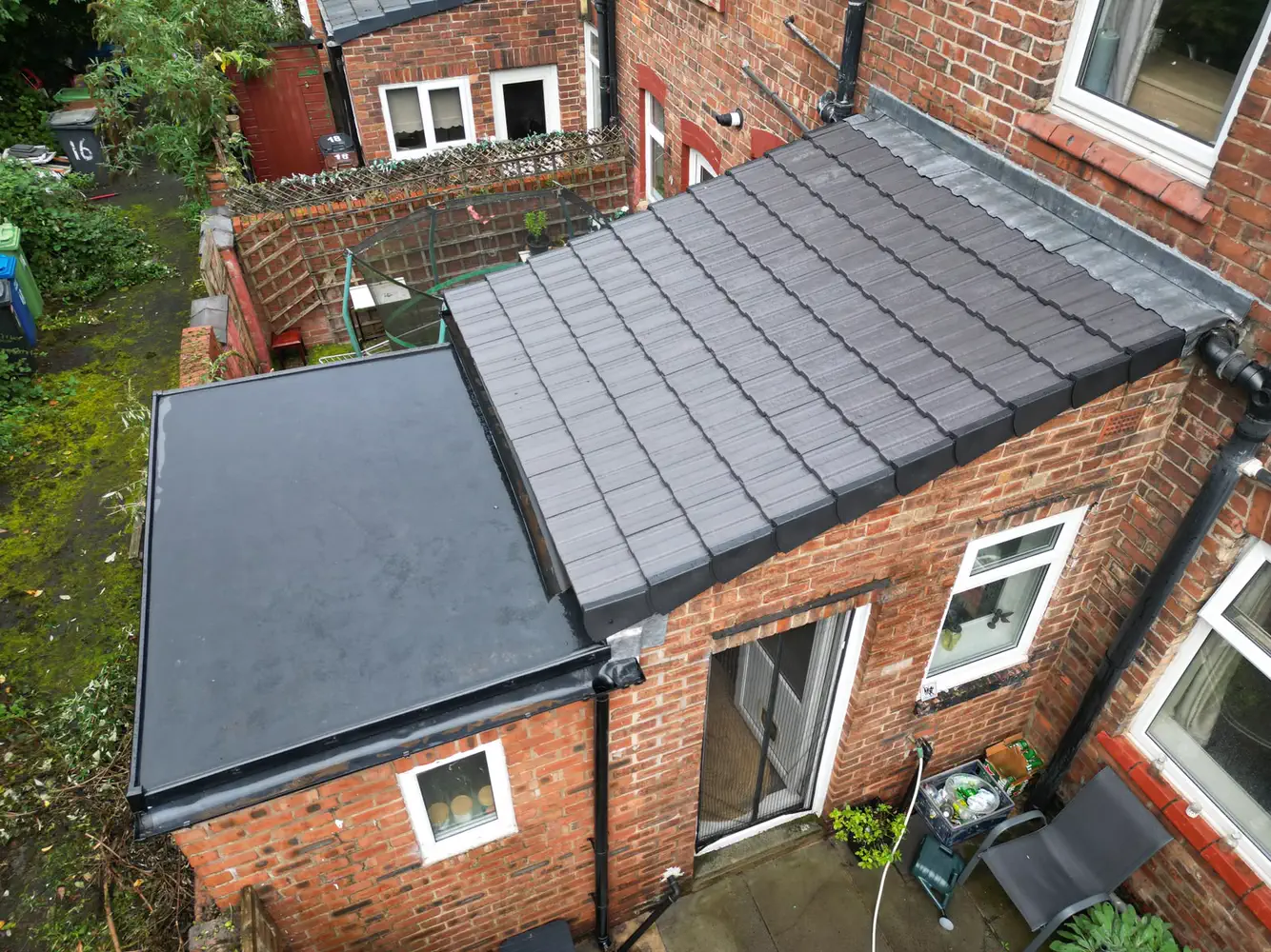 A rear extension with a flat roof beside a grey tiled lean-to roof, seen from the air